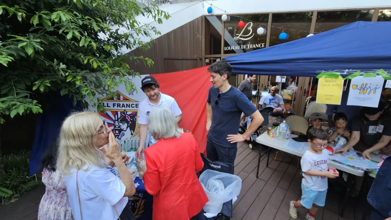 Visitors and AFRC members gather around the All France Rugby Club stand during the French Embassy’s Bastille Day celebration in Tokyo.