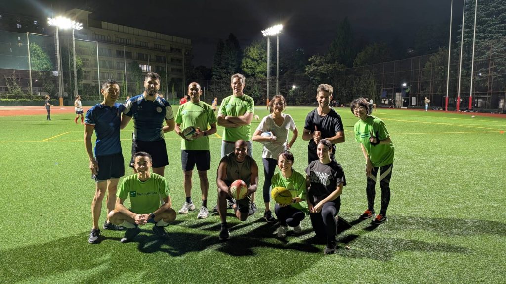 BNP Paribas colleagues and AFRC coaches posing together on the rugby pitch after the touch rugby session in Tokyo.