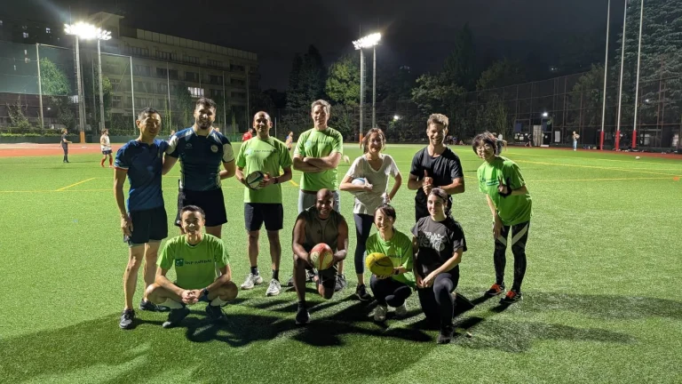 BNP Paribas colleagues and AFRC coaches posing together on the rugby pitch after the touch rugby session in Tokyo.